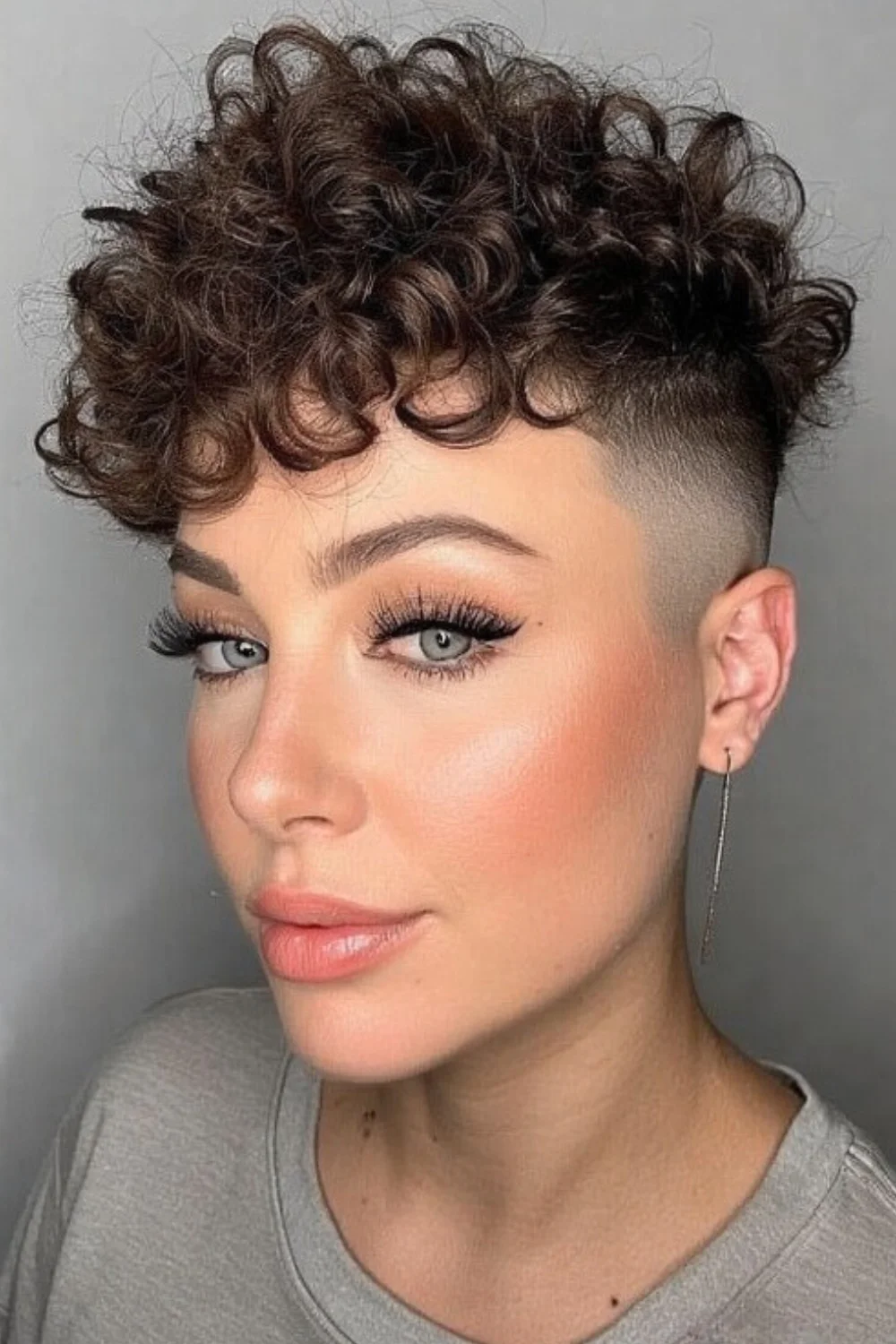 Curly undercut hairstyle with a sharp, edgy finish.